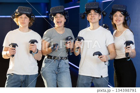 Friends in virtual reality glasses holding joysticks after playing virtual games 134398791