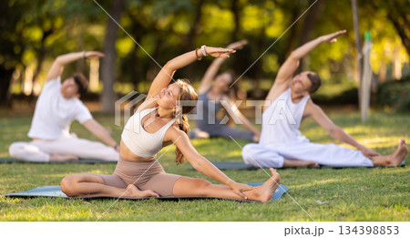Girl participating in outdoor group yoga session in summer park Girl participating in outdoor group yoga session in summer park 134398853