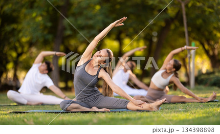 Woman participating in outdoor group yoga session in city park 134398898