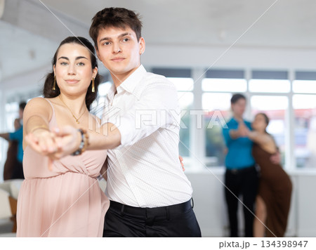 Couple in evening dresses enjoys pair dance tango, interacting with each other on floor Couple in evening dresses enjoys pair dance tango, interacting with each other on floor 134398947