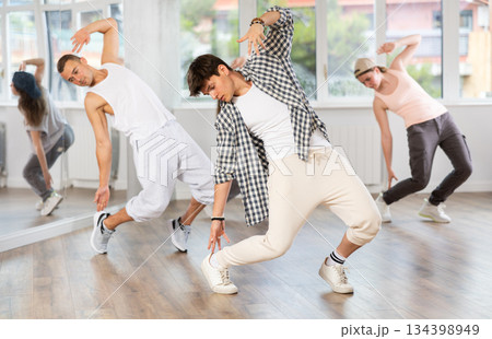 Young man standing performs basic hip hop movements in front of group of students 134398949