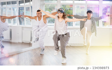 Active men and girls practicing hip-hop dance in training hall during group dancing classes Active men and girls practicing hip-hop dance in training hall during group dancing classes 134398973