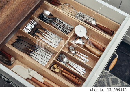 Bamboo organizer with cutlery in kitchen drawer 134399113