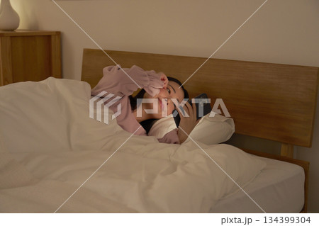 布団の中でスマホを使う女性　眠気 134399304