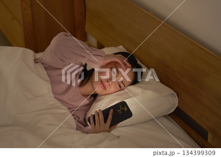布団の中でスマホを見る女性 布団の中でスマホを見る女性 134399309