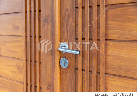 Stainless steel door handle on wooden door. Stainless steel door handle on wooden door. 134399332
