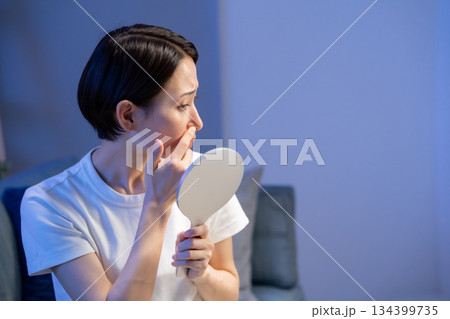手鏡を見て悩む女性 134399735