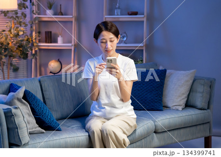 リビングでスマホを見る女性 134399741