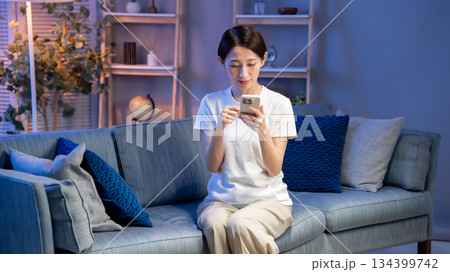 リビングでスマホを見る女性 134399742