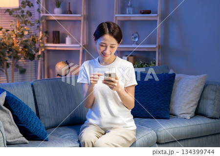 リビングでスマホを見る女性 134399744