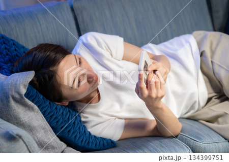 ソファーに寝そべりスマホを見る女性 ソファーに寝そべりスマホを見る女性 134399751