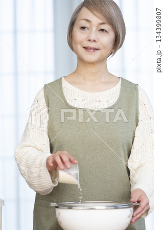 キッチンでご飯を炊く準備をするシニア女性 キッチンでご飯を炊く準備をするシニア女性 134399807