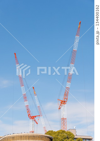 3基の赤白に塗装された建設用クレーンと青空 134400162