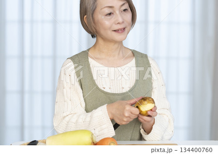 キッチンで野菜の皮を剥くシニア女性 134400760