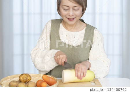 キッチンで野菜の皮を剥くシニア女性 キッチンで野菜の皮を剥くシニア女性 134400762