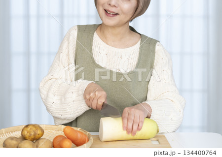 キッチンで野菜の皮を剥くシニア女性 キッチンで野菜の皮を剥くシニア女性 134400764
