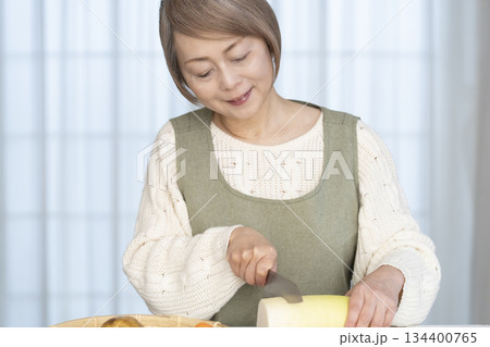 キッチンで野菜の皮を剥くシニア女性 134400765