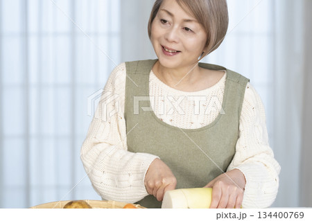 キッチンで野菜の皮を剥くシニア女性 134400769