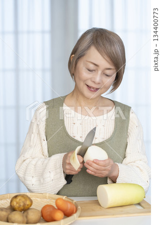 キッチンで野菜の皮を剥くシニア女性 キッチンで野菜の皮を剥くシニア女性 134400773