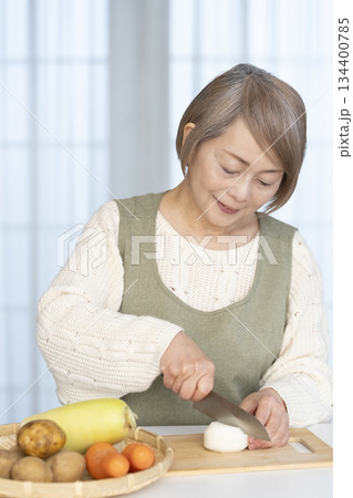 キッチンで野菜の皮を剥くシニア女性 キッチンで野菜の皮を剥くシニア女性 134400785