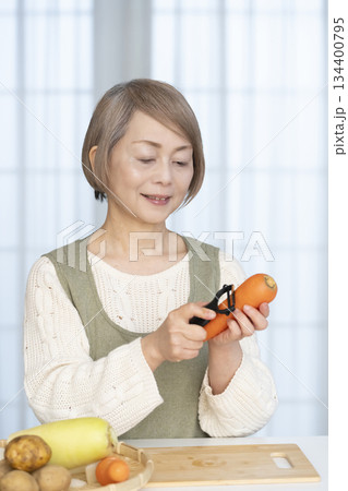 キッチンで野菜の皮を剥くシニア女性 134400795
