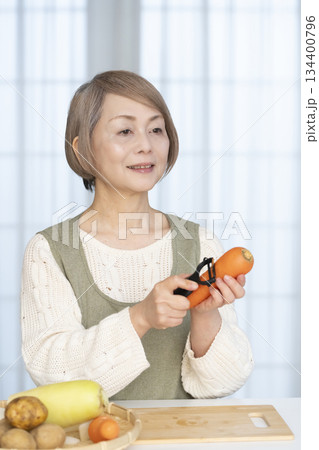 キッチンで野菜の皮を剥くシニア女性 134400796