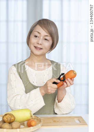 キッチンで野菜の皮を剥くシニア女性 キッチンで野菜の皮を剥くシニア女性 134400797