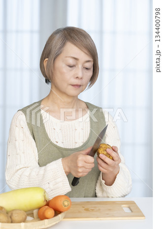 キッチンで野菜の皮を剥くシニア女性 134400798