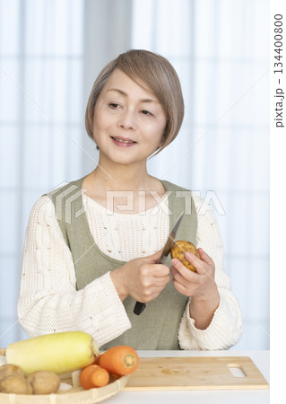 キッチンで野菜の皮を剥くシニア女性 キッチンで野菜の皮を剥くシニア女性 134400800