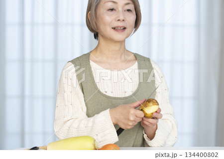 キッチンで野菜の皮を剥くシニア女性 キッチンで野菜の皮を剥くシニア女性 134400802