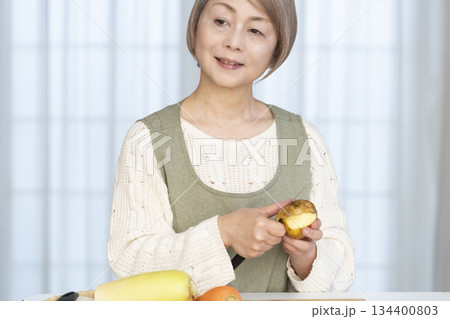 キッチンで野菜の皮を剥くシニア女性 キッチンで野菜の皮を剥くシニア女性 134400803