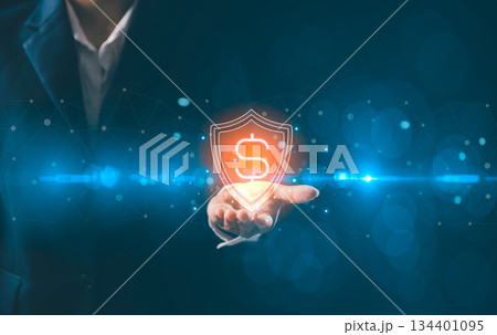 Business professional holding glowing holographic shield with dollar symbol, representing financial security, fintech protection, safe transactions, digital banking and modern financial data safety. Business professional holding glowing holographic shield with dollar symbol, representing financial security, fintech protection, safe transactions, digital banking and modern financial data safety. 134401095