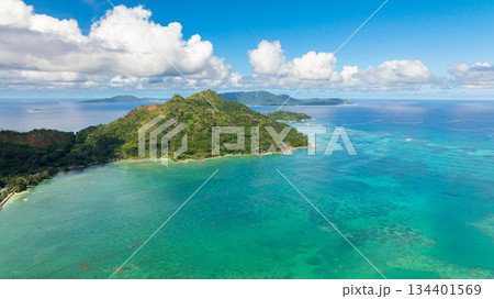 An island with dense green vegetation sits amidst the turquoise waters dotted with distant islands. Praslin, Seychelles. 134401569