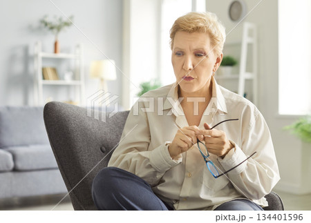 Thoughtful And Sad Elderly Woman Sitting At Home In Despair 134401596