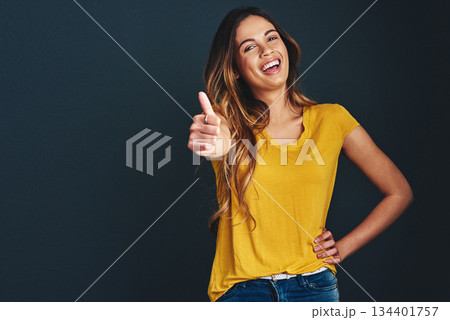 Happy, portrait and a woman with a thumbs up for success, agreement and yes sign. Smile, thank you and a lady with a hand gesture isolated on a dark background in a studio with mockup for motivation 134401757