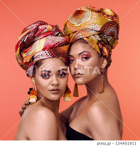 African fashion, makeup and portrait of women on orange background for cosmetics, beauty and accessory. Glamour, designer and face of female people in exotic jewelry, luxury style and scarf in studio African fashion, makeup and portrait of women on orange background for cosmetics, beauty and accessory. Glamour, designer and face of female people in exotic jewelry, luxury style and scarf in studio 134401911
