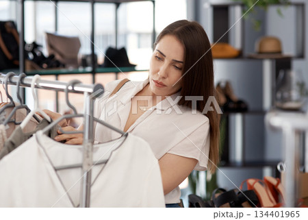 Shopping, store and a woman customer in a mall boutique to buy trendy clothes for seasonal fashion. Search, retail and sale with a young female consumer in a shop, making a clothing purchase choice Shopping, store and a woman customer in a mall boutique to buy trendy clothes for seasonal fashion. Search, retail and sale with a young female consumer in a shop, making a clothing purchase choice 134401965