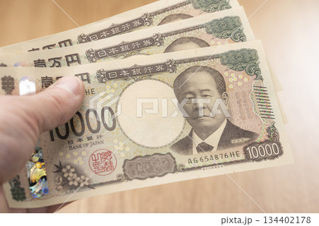 一万円札を手に持つ日本円の現金と資金イメージ 一万円札を手に持つ日本円の現金と資金イメージ 134402178