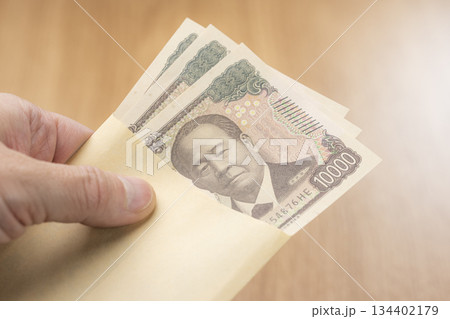 封筒から一万円札を取り出す手元が示す日本円の支払いイメージ 134402179