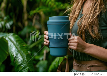 Young Woman Holding Reusable Silicone Coffee Cup Surrounded by Lush Greenery 134402322