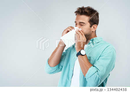 Allergy, sick and man blowing nose in tissue with flu, illness and virus on studio background. Health mockup, wellness and face of male person with handkerchief for hayfever sinus, cold and sneeze 134402438