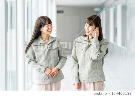 スマホで通話する作業着,作業衣服を着た製造業・建築業・運送業・建設業の女性スタッフ 134403152