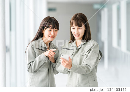 スマホを見る作業着,作業衣服を着た製造業・建築業・運送業・建設業の女性スタッフ 134403153