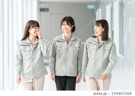 オフィスビルの通路を歩く作業着姿の製造業・建築業・運送業・建設業の女性スタッフ 134403160