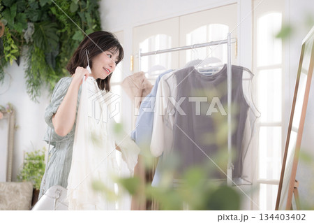 洋服を手に取り笑顔で選ぶ若い女性のガーリーファッションライフスタイル 洋服を手に取り笑顔で選ぶ若い女性のガーリーファッションライフスタイル 134403402