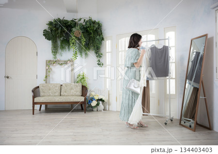 洋服を手に取り笑顔で選ぶ若い女性のファッションライフスタイル 鏡を見る 洋服を手に取り笑顔で選ぶ若い女性のファッションライフスタイル 鏡を見る 134403403
