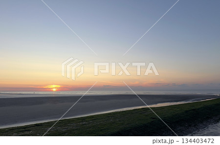 A Serene Beach Sunset Over the Calm Waters, creating a tranquil and picturesque atmosphere A Serene Beach Sunset Over the Calm Waters, creating a tranquil and picturesque atmosphere 134403472