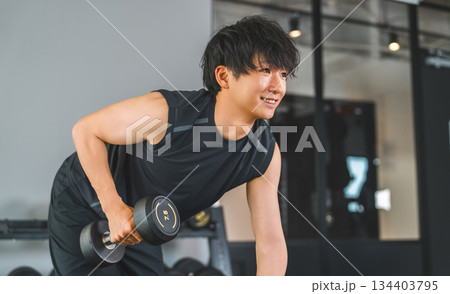 フィットネスジムでダンベルトレーニングをする若いアジア人男性 フィットネスジムでダンベルトレーニングをする若いアジア人男性 134403795