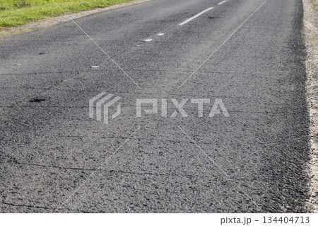 A quiet rural road stretches into the distance, showing fresh asphalt A quiet rural road stretches into the distance, showing fresh asphalt 134404713