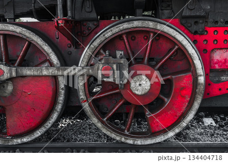 A detailed view of a red steam locomotive wheel set, showing weathered metal 134404718